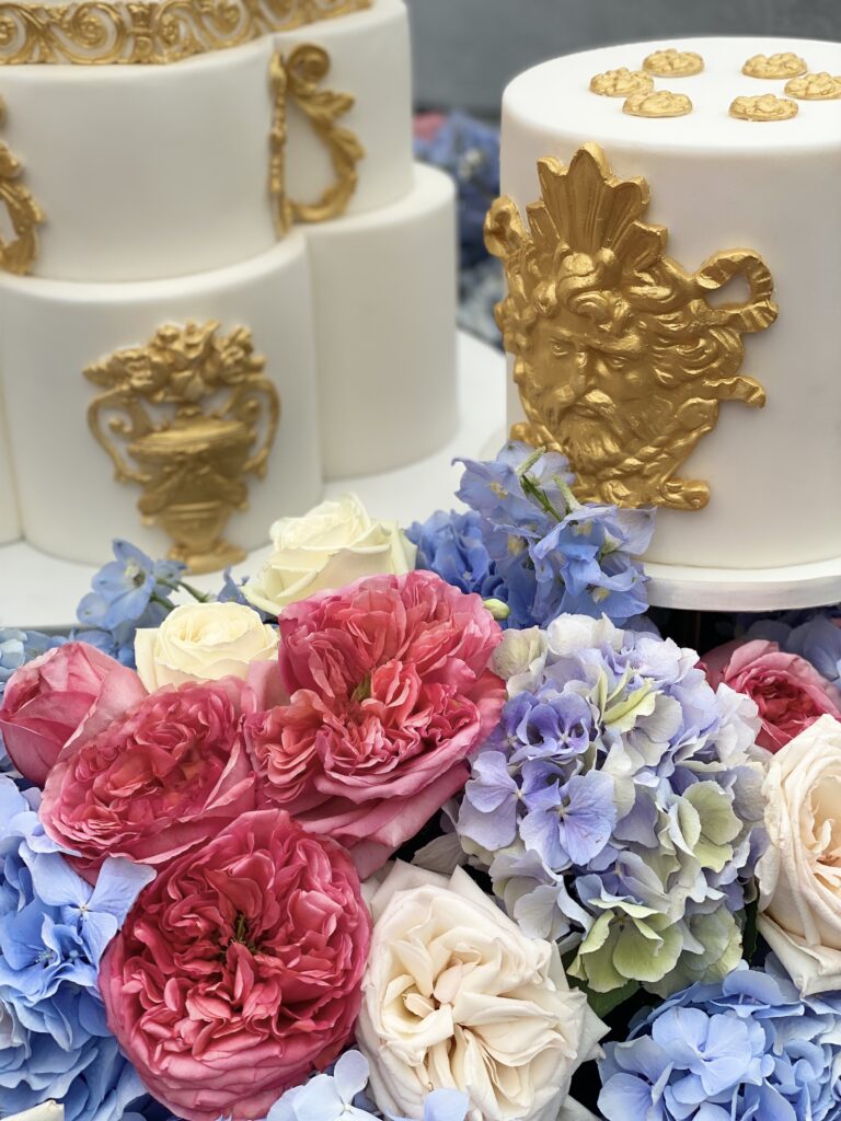 Gold and white cake with hydrangeas, roses and agapanthus flowers